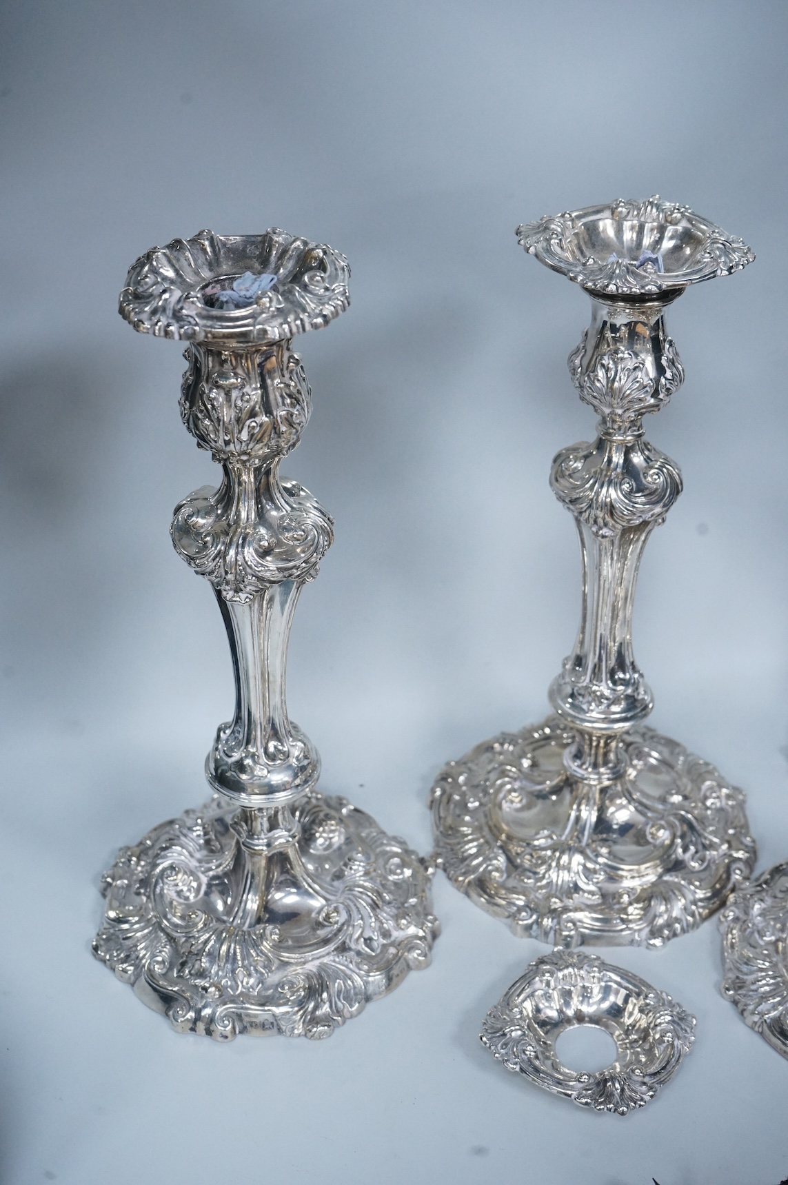 Two similar pairs of George III silver candlesticks, both with fluted tapered columns and decorated with foliage and scrolls, fixed sconces, makers mark rubbed, Sheffield, 1814 and S.C. Younge & Co, Sheffield, 1816, 28.5